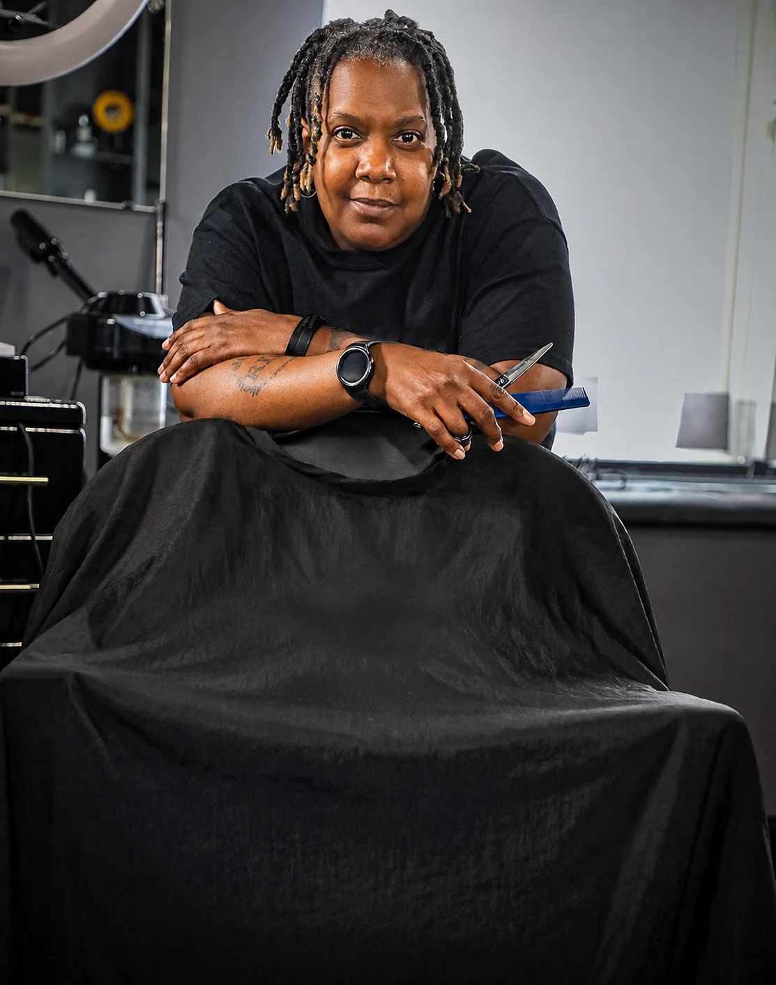 Ayesha Blackledge holding her comb and shears at a barber chair